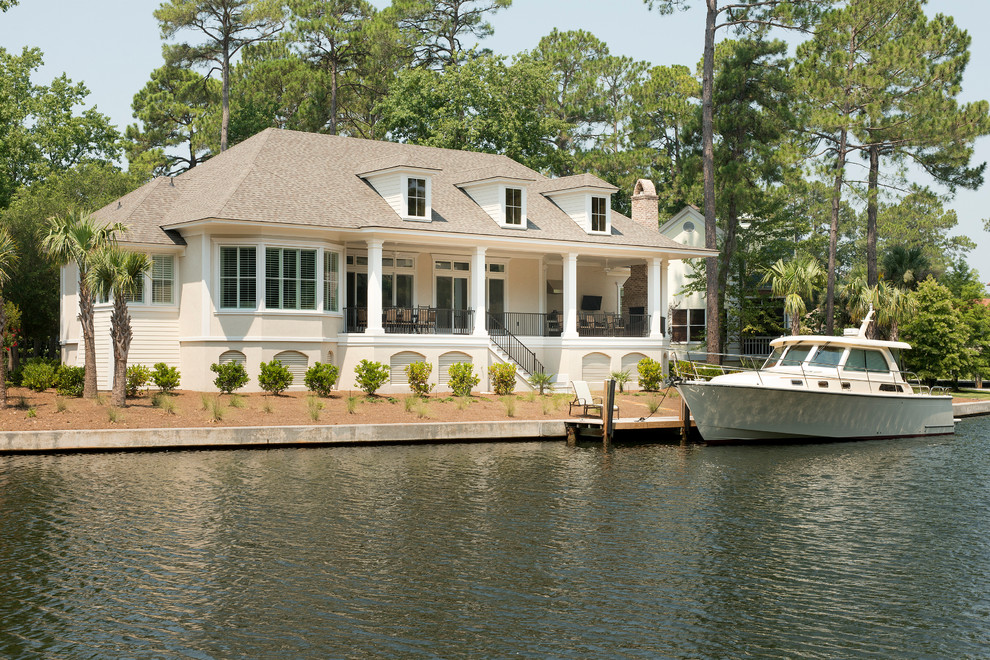 Cette image montre une façade de maison beige marine à un étage avec un toit à quatre pans.