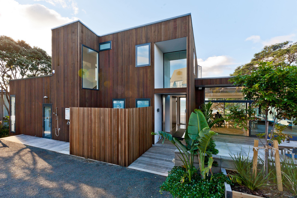 This is an example of a brown contemporary split-level house exterior in Hamilton with wood cladding and a flat roof.