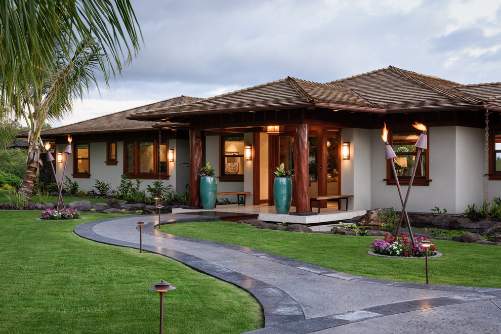 ハワイにあるラグジュアリーなトロピカルスタイルのおしゃれな家の外観 (漆喰サイディング) の写真