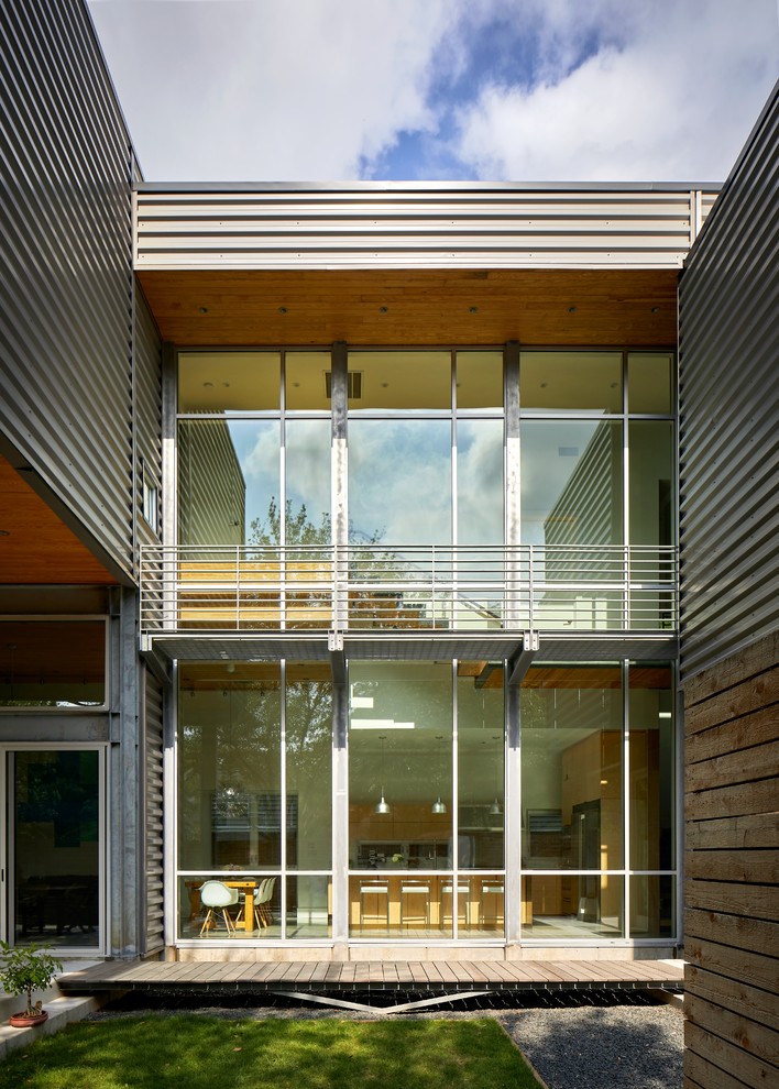 Bild på ett mellanstort funkis hus, med två våningar och glasfasad