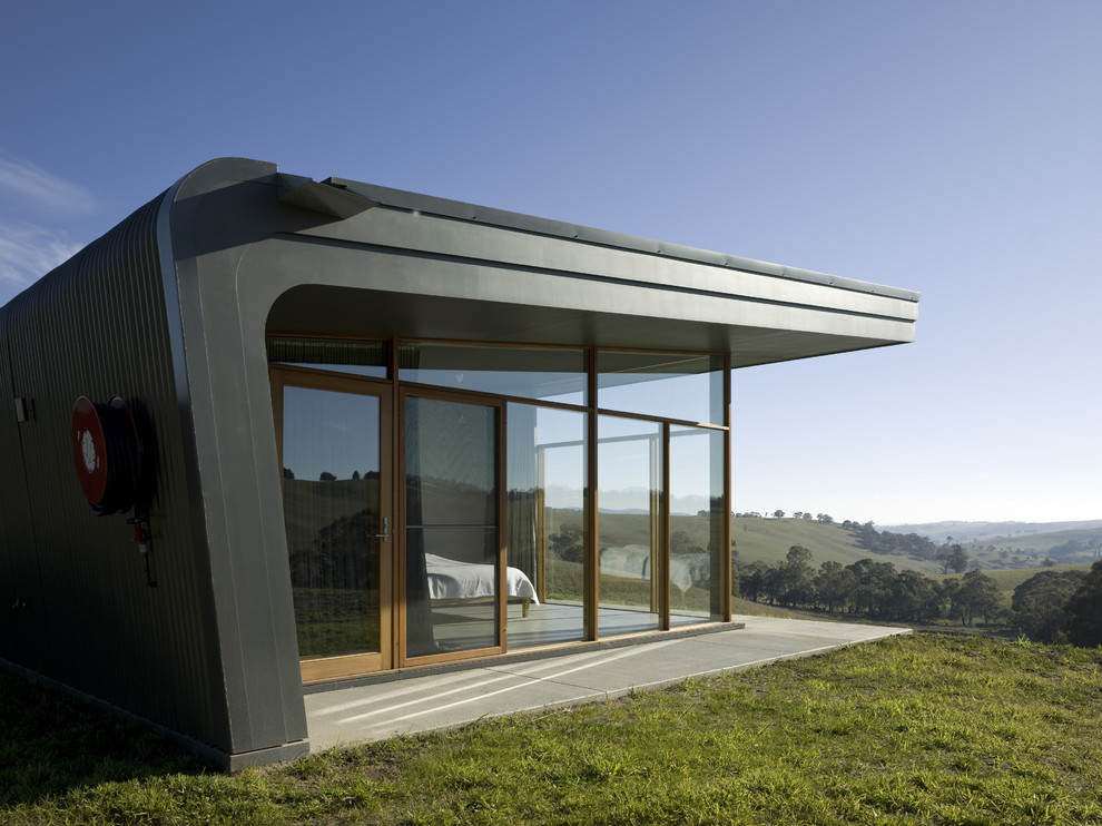На фото: одноэтажный, стеклянный дом среднего размера в современном стиле с односкатной крышей