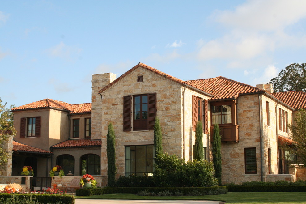 This is an example of a large and beige mediterranean two floor detached house in Dallas with stone cladding, a hip roof and a tiled roof.
