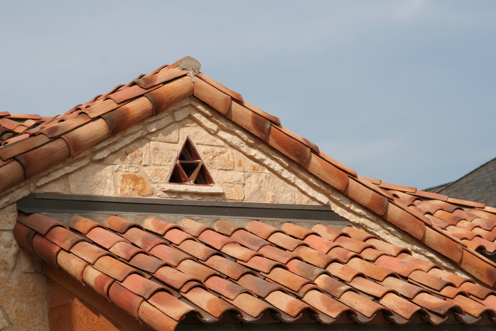 Ejemplo de fachada de casa beige mediterránea grande de dos plantas con revestimiento de piedra, tejado a cuatro aguas y tejado de teja de barro