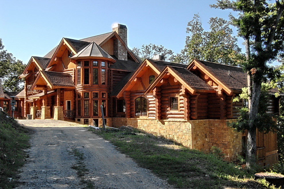 Imagen de fachada marrón rústica extra grande de tres plantas con revestimiento de madera y tejado a cuatro aguas