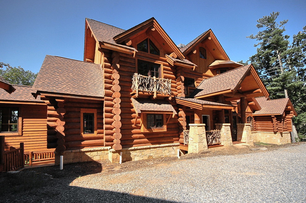 Foto de fachada marrón rústica extra grande de tres plantas con revestimiento de madera y tejado a cuatro aguas