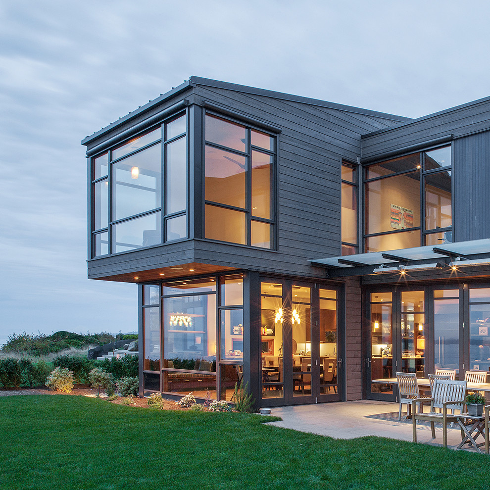 Cette photo montre une façade de maison grise tendance en bois de taille moyenne et à un étage avec un toit en appentis.