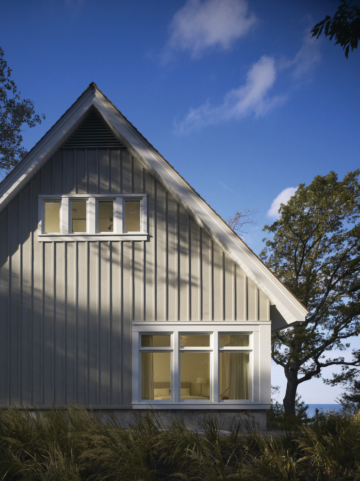 Cette image montre une façade de maison grise traditionnelle en bois de taille moyenne et à un étage avec un toit à deux pans.