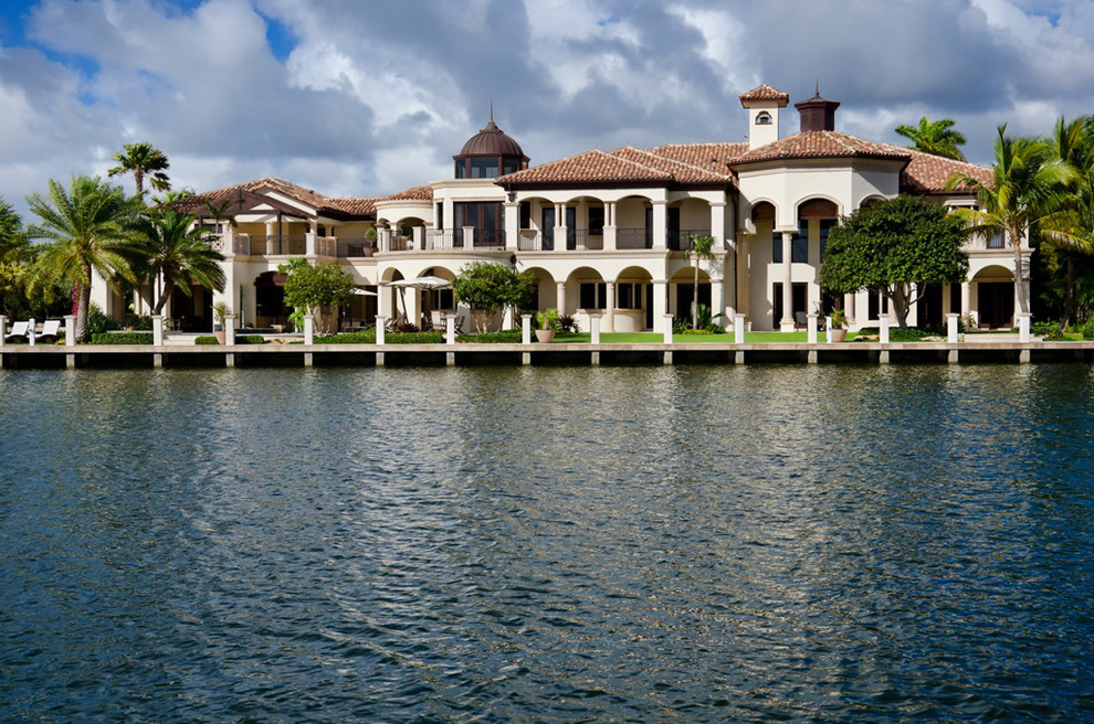 Example of a huge tuscan beige two-story stucco exterior home design in Miami