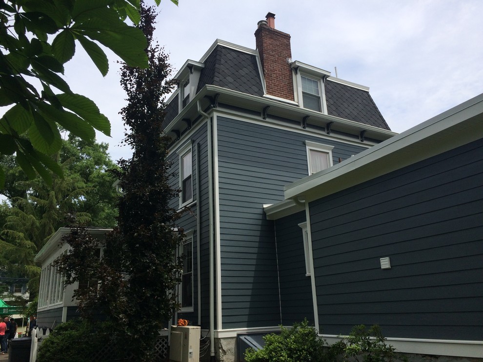 This is an example of a medium sized and blue victorian house exterior in New York with three floors, concrete fibreboard cladding and a hip roof.