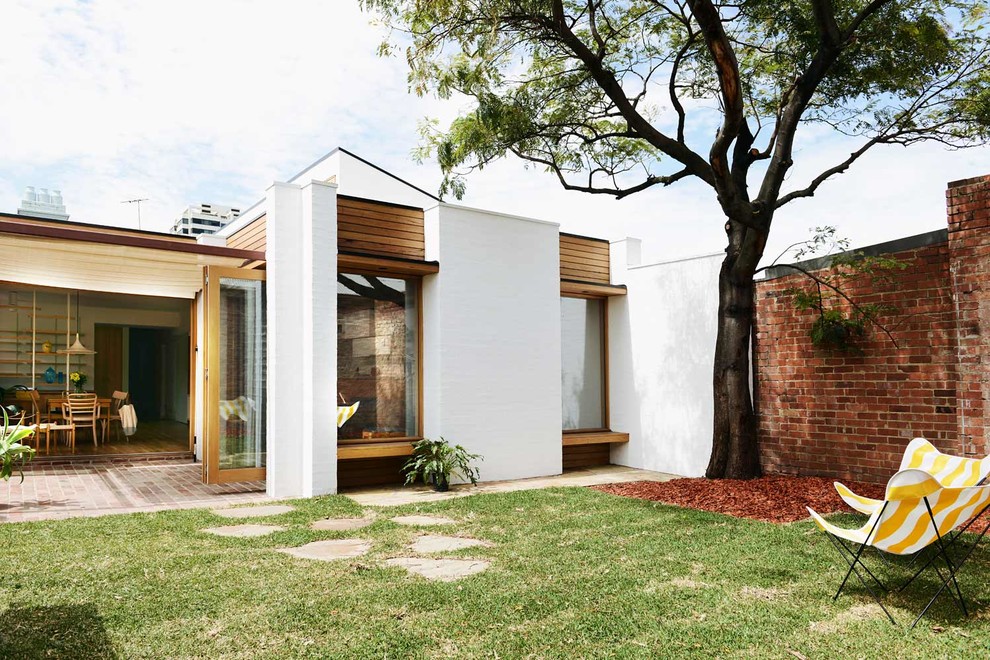 Aménagement d'une façade de maison blanche scandinave en brique de taille moyenne et de plain-pied avec un toit plat.