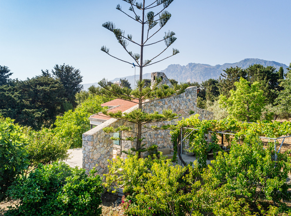 На фото: маленький, одноэтажный, белый мини дом в средиземноморском стиле с облицовкой из цементной штукатурки, односкатной крышей и черепичной крышей для на участке и в саду