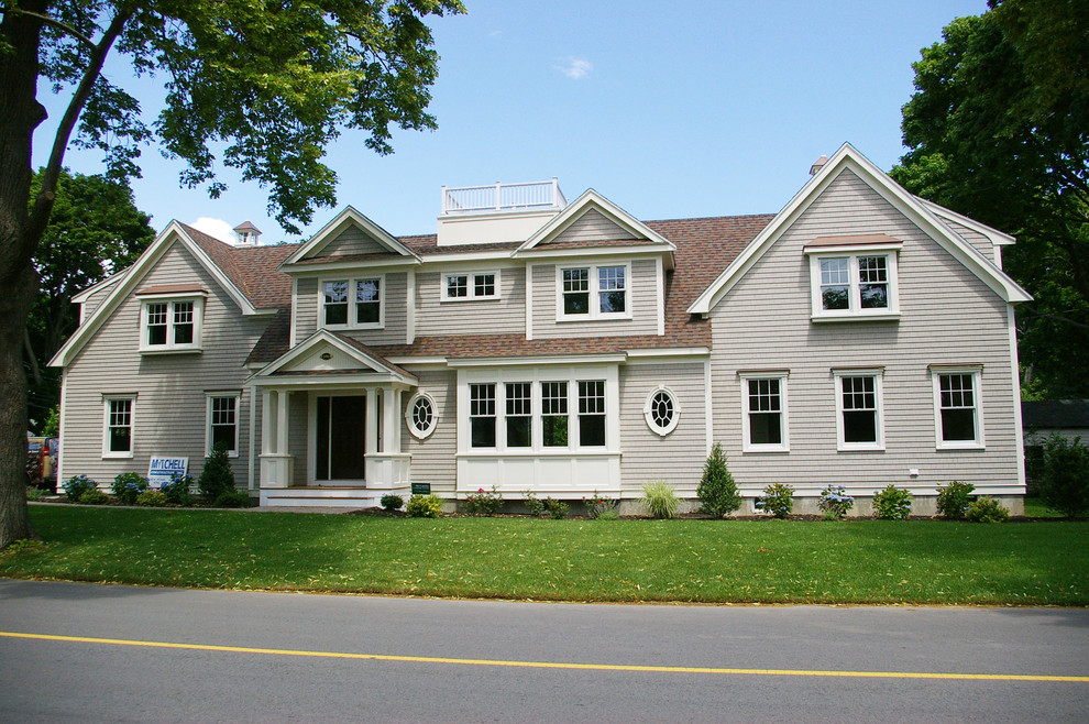 Cette photo montre une grande façade de maison beige chic en bois à un étage avec un toit à deux pans et un toit en shingle.