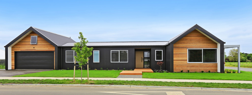 Réalisation d'une façade de maison noire minimaliste en bois de taille moyenne et de plain-pied avec un toit à deux pans, un toit en métal et un toit noir.
