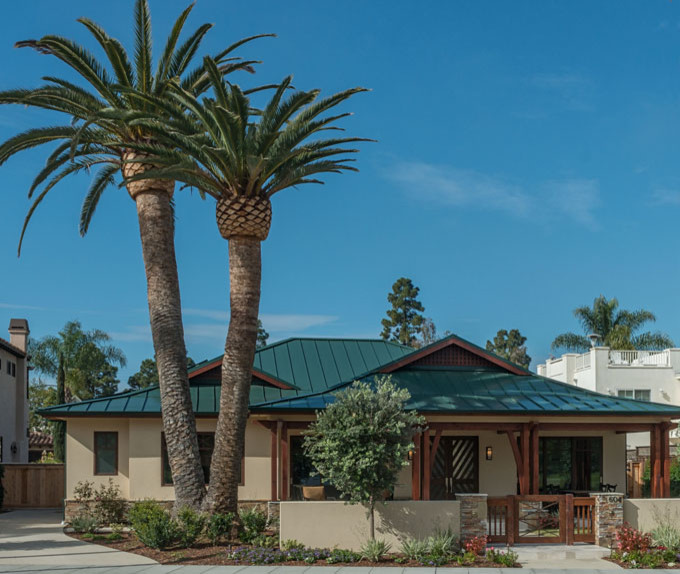 Example of a large island style beige one-story stone gable roof design in San Diego