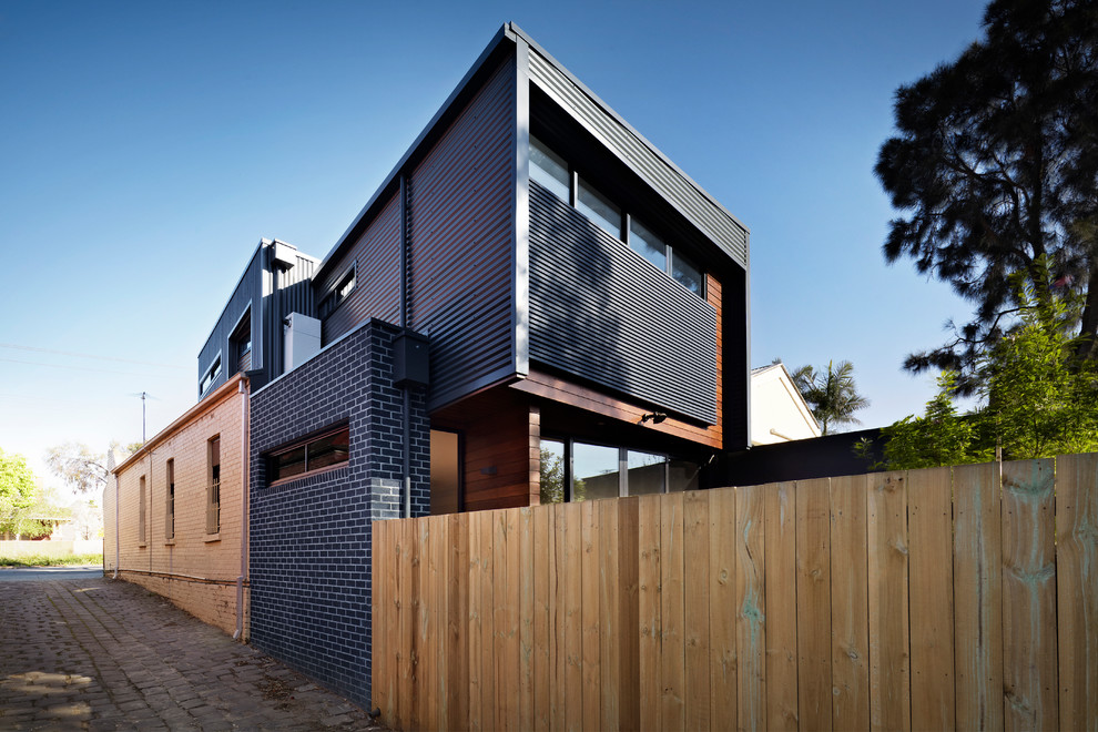 Cette photo montre une grande façade de maison métallique et grise tendance à un étage avec un toit plat et un toit en métal.