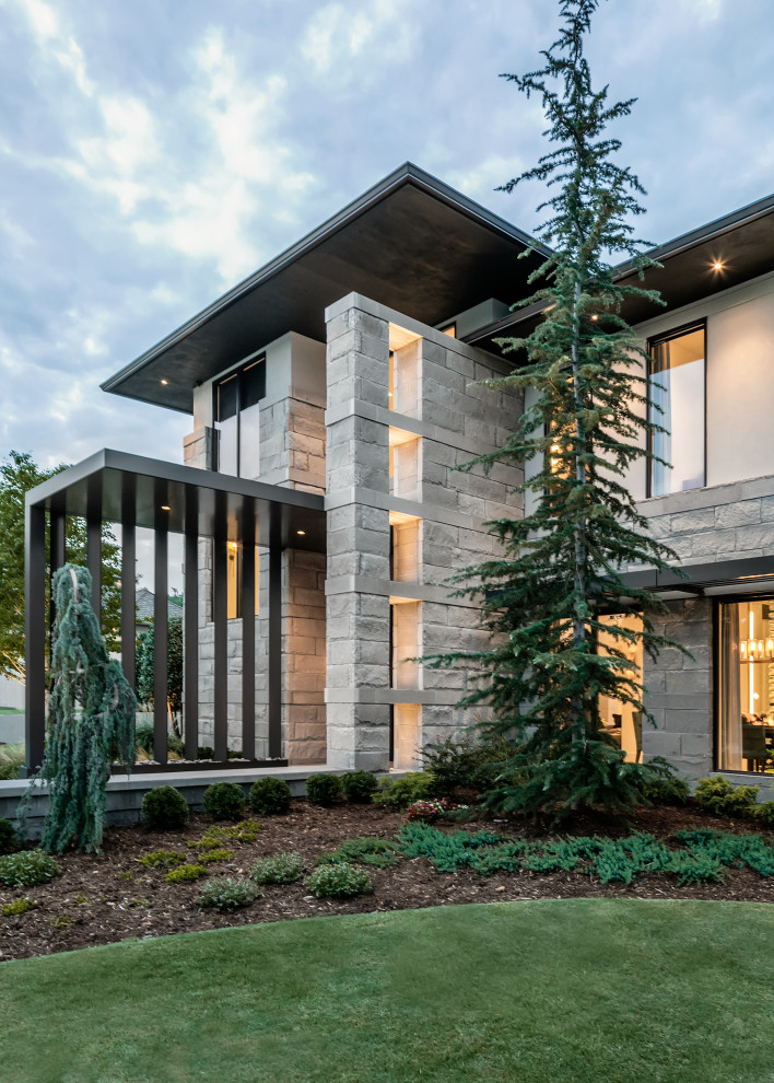 На фото: большой, двухэтажный, серый частный загородный дом в стиле модернизм с облицовкой из цементной штукатурки