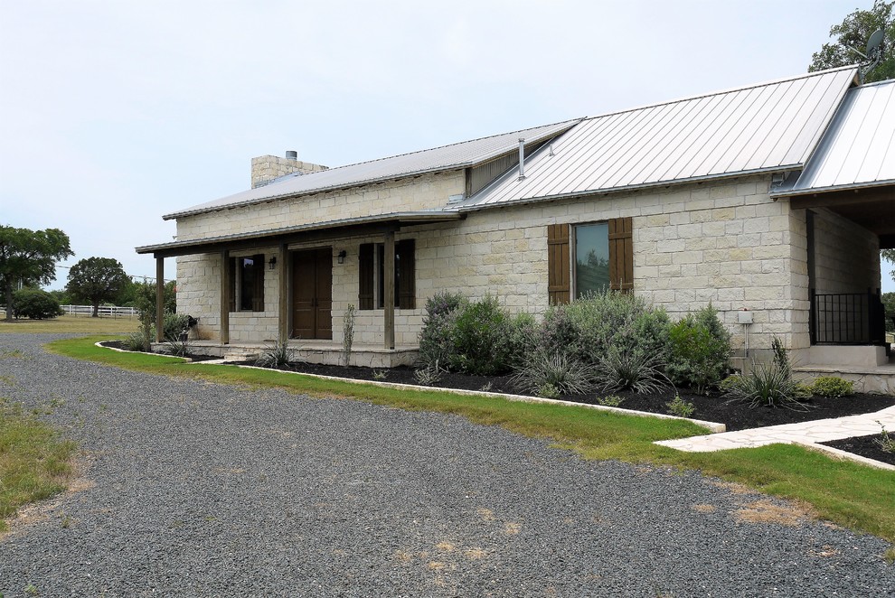 Foto de fachada de casa beige rústica grande de una planta con revestimiento de piedra, tejado a dos aguas y tejado de metal