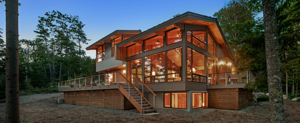 Cette image montre une grande façade de maison design à un étage avec un revêtement mixte, un toit à deux pans et un toit en métal.