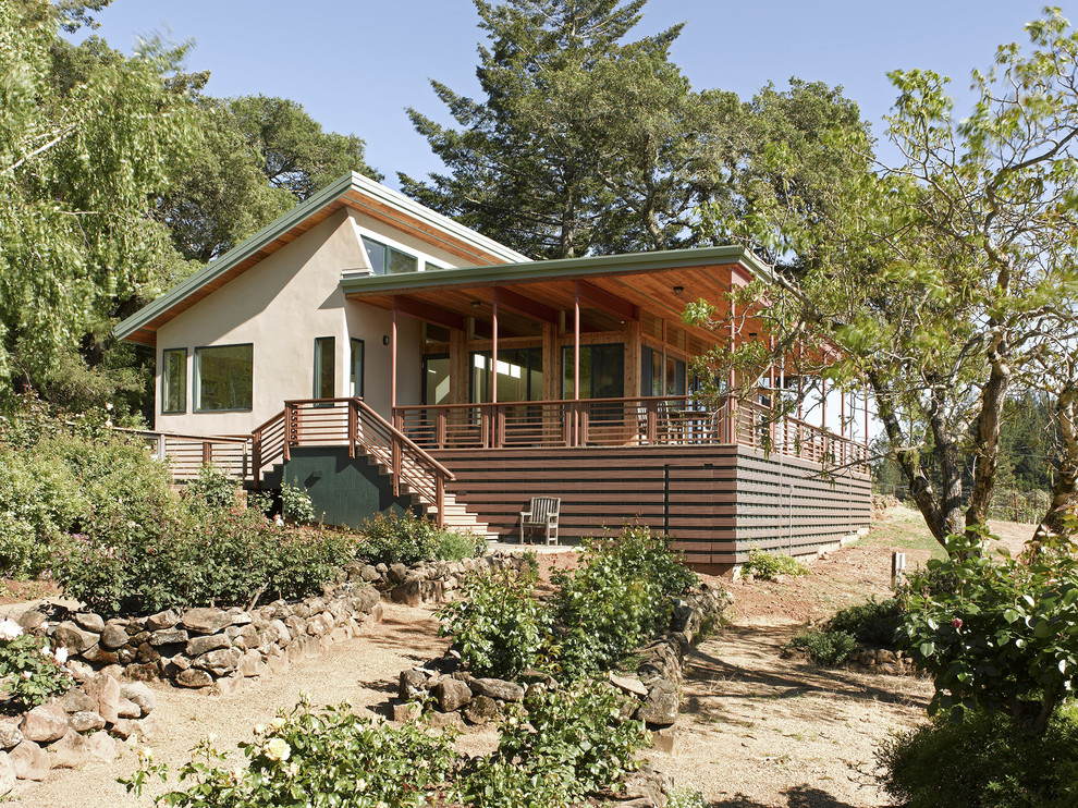 Cette photo montre une façade de maison beige moderne en stuc de taille moyenne et de plain-pied avec un toit plat.
