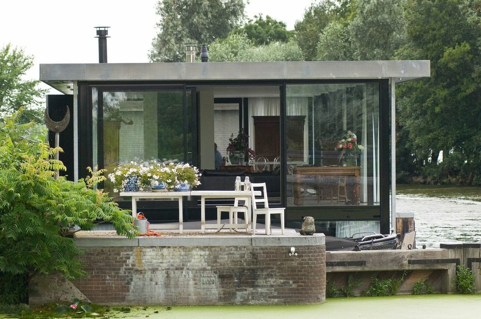 Esempio della facciata di una casa contemporanea a un piano di medie dimensioni con rivestimento in vetro e tetto piano