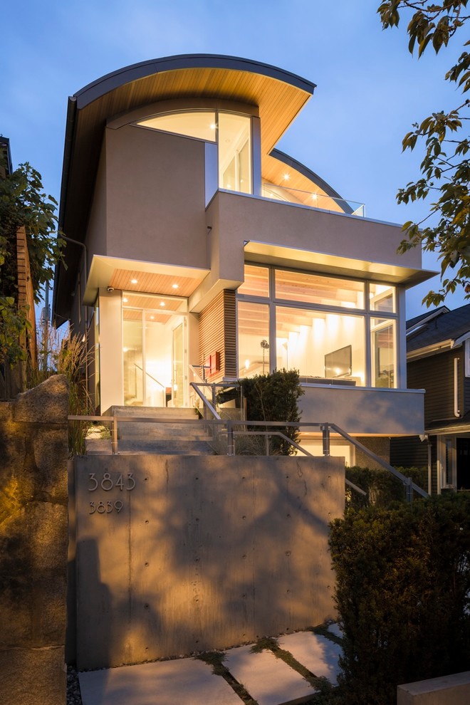 Inspiration pour une façade de maison grise design en stuc de taille moyenne et à deux étages et plus.