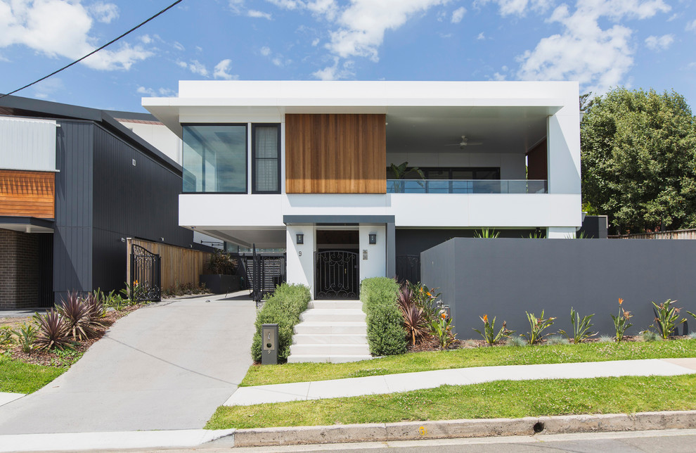 Réalisation d'une grande façade de maison blanche minimaliste à deux étages et plus avec un toit plat et un toit en métal.