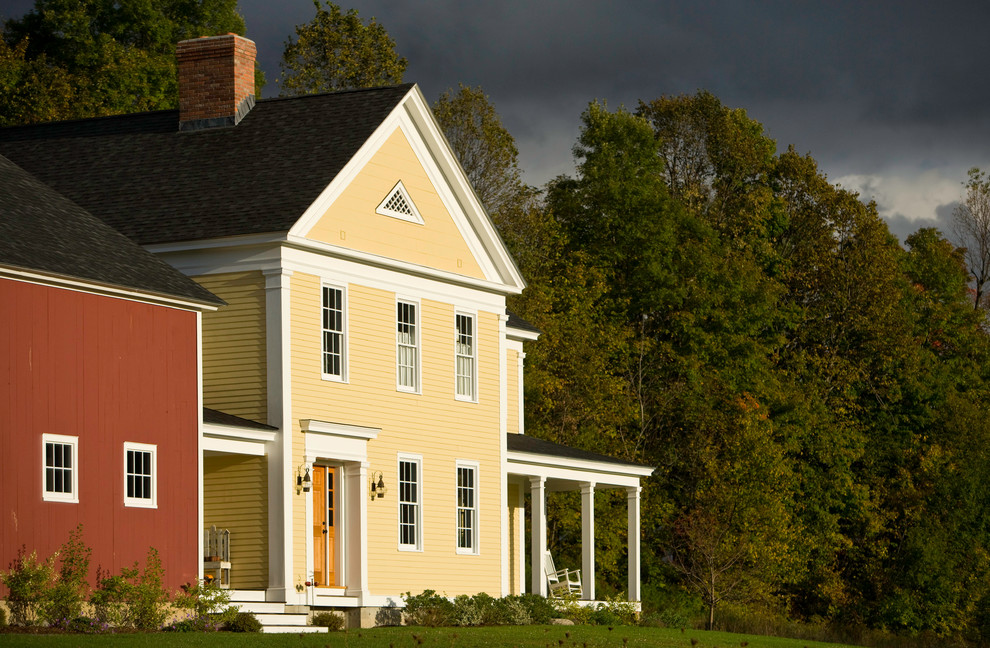 Стильный дизайн: двухэтажный, желтый дом в стиле кантри с двускатной крышей - последний тренд