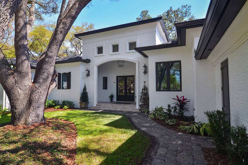Expansive and white contemporary bungalow detached house in Tampa with mixed cladding, a hip roof and a shingle roof.