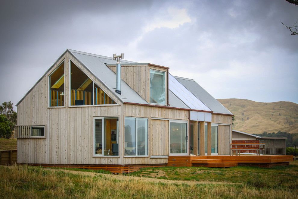 На фото: маленький, деревянный, серый частный загородный дом в морском стиле с разными уровнями, двускатной крышей и металлической крышей для на участке и в саду с
