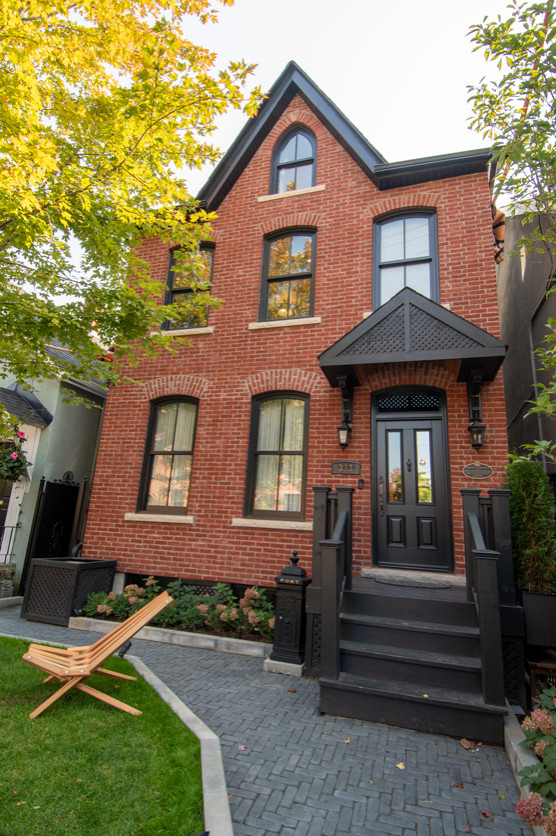Mittelgroßes, Dreistöckiges Klassisches Einfamilienhaus mit Putzfassade, roter Fassadenfarbe, Satteldach, Schindeldach und blauem Dach in Toronto