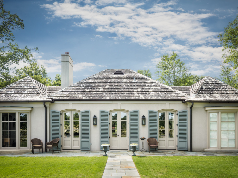 Imagen de fachada blanca clásica de tamaño medio de una planta con revestimiento de estuco y tejado a cuatro aguas