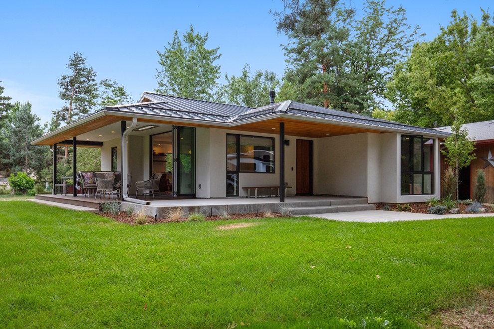Réalisation d'une façade de maison beige minimaliste en stuc de taille moyenne et de plain-pied avec un toit en métal.