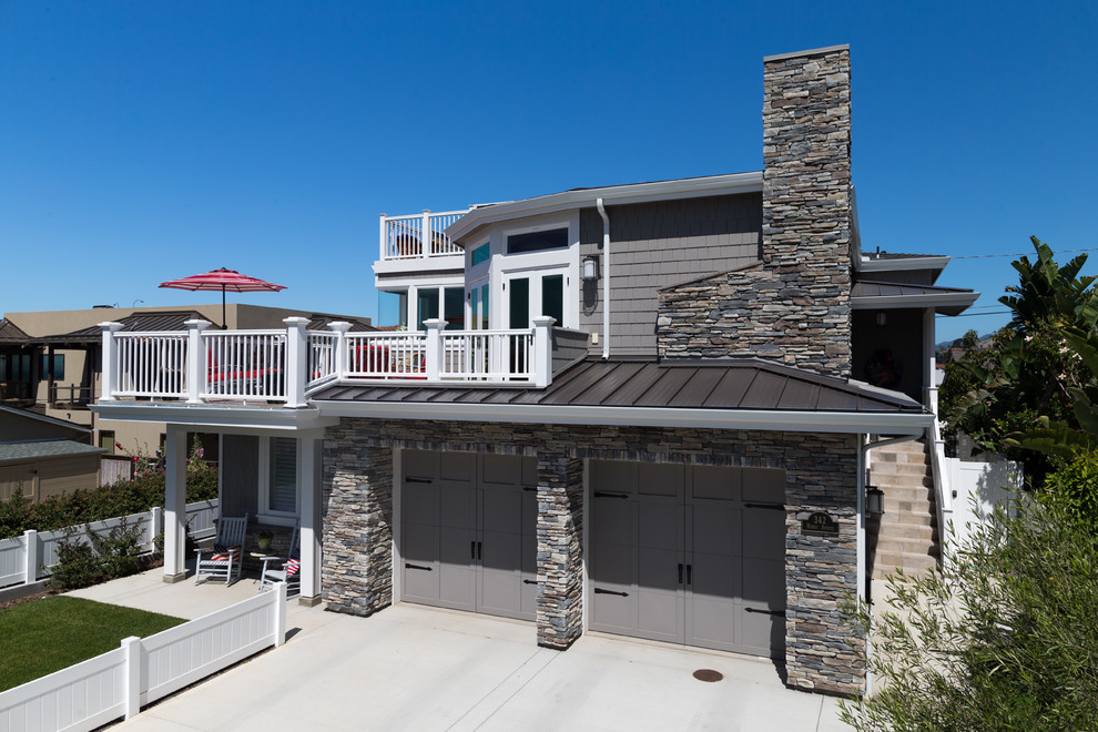 Cette photo montre une grande façade de maison grise bord de mer à un étage avec un revêtement mixte, un toit à quatre pans et un toit en métal.