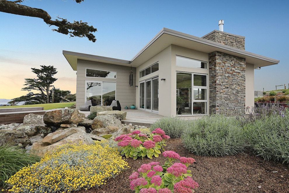 Diseño de fachada de casa beige moderna grande de una planta con tejado plano y tejado de metal