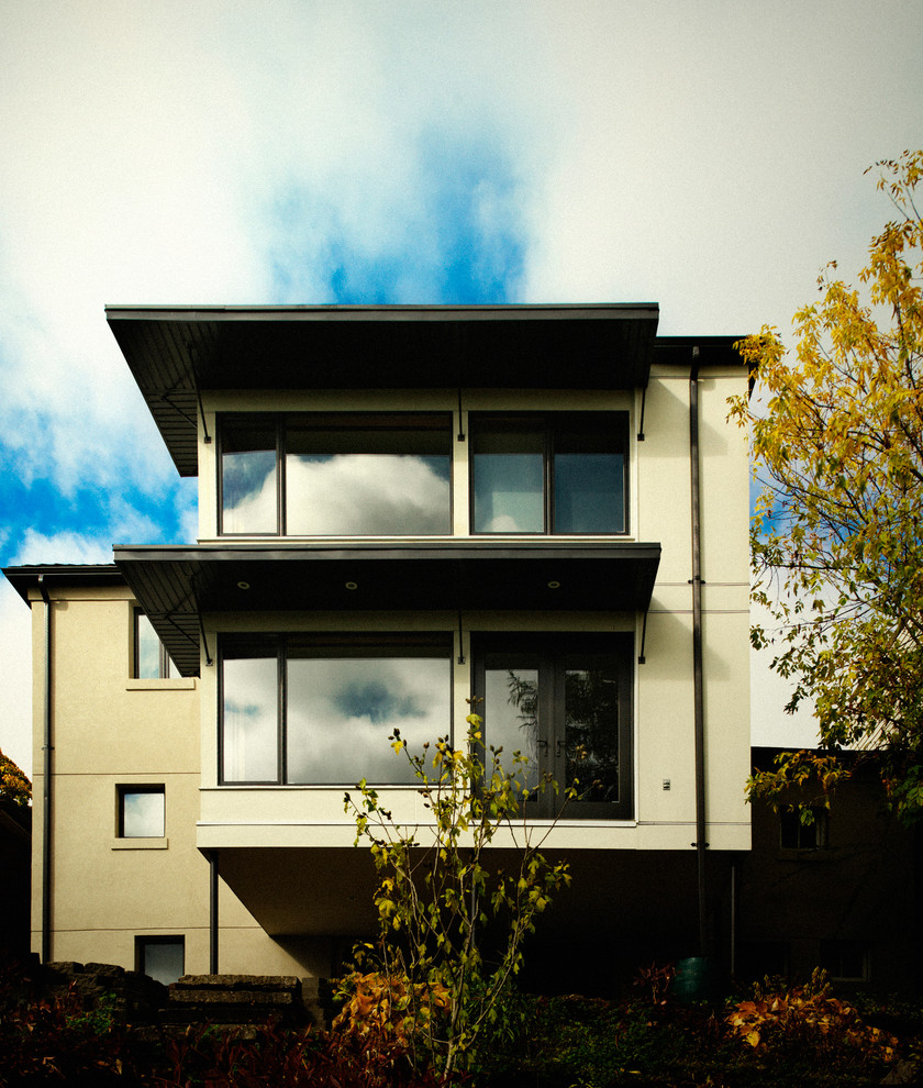 Immagine della facciata di una casa grigia moderna a due piani con rivestimento in stucco e tetto piano