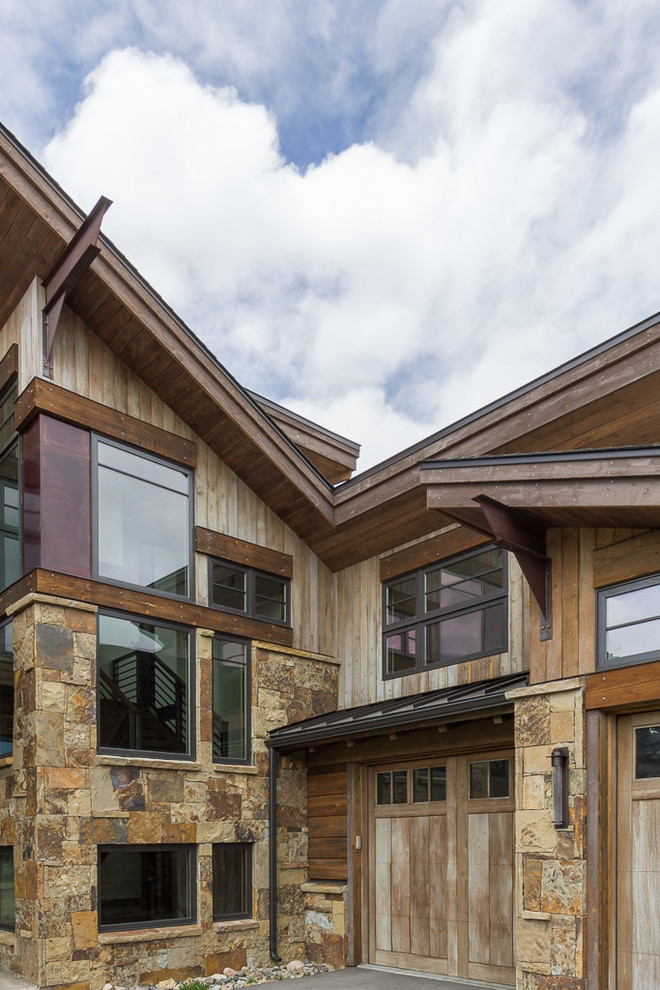 Idée de décoration pour une grande façade de maison marron design en bois à un étage.
