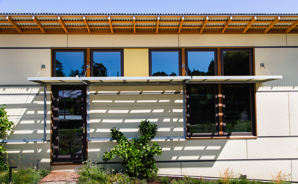 Inspiration för moderna gula hus i flera nivåer, med fiberplattor i betong och pulpettak