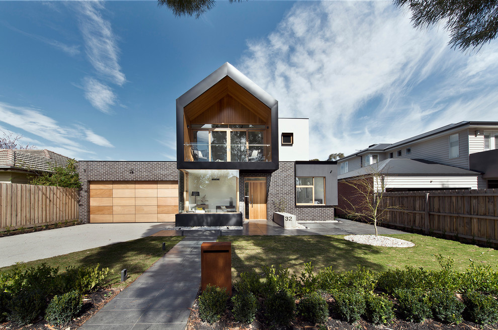 Réalisation d'une grande façade de maison métallique et noire minimaliste à un étage.