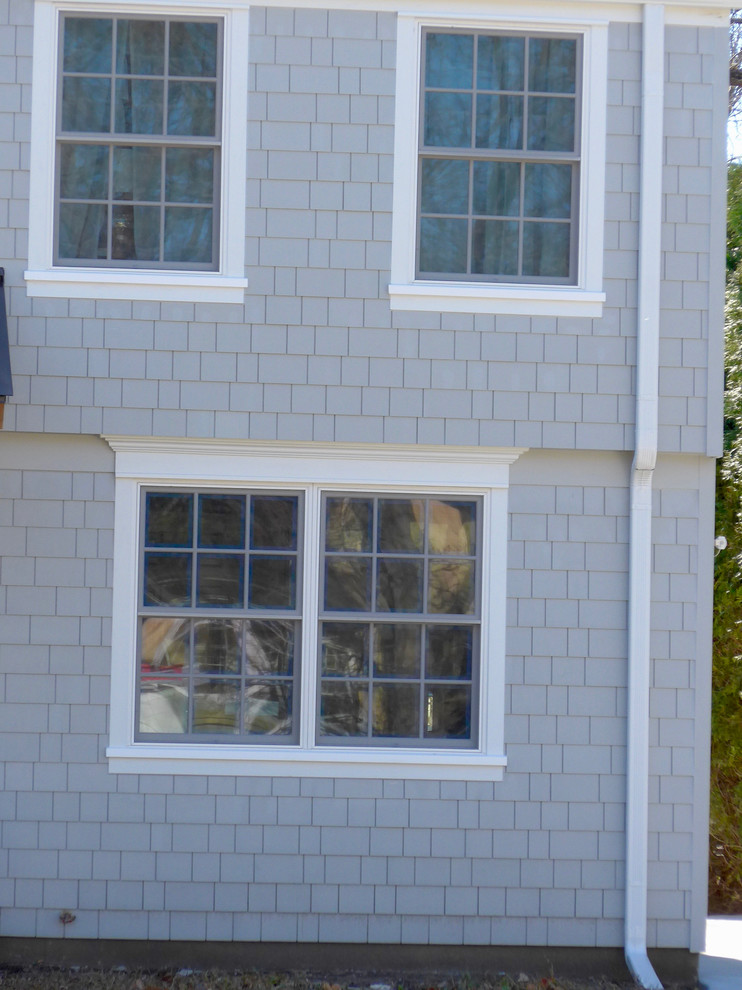 Modelo de fachada de casa gris tradicional de tamaño medio de dos plantas con revestimiento de aglomerado de cemento, tejado de teja de madera y tejado a dos aguas