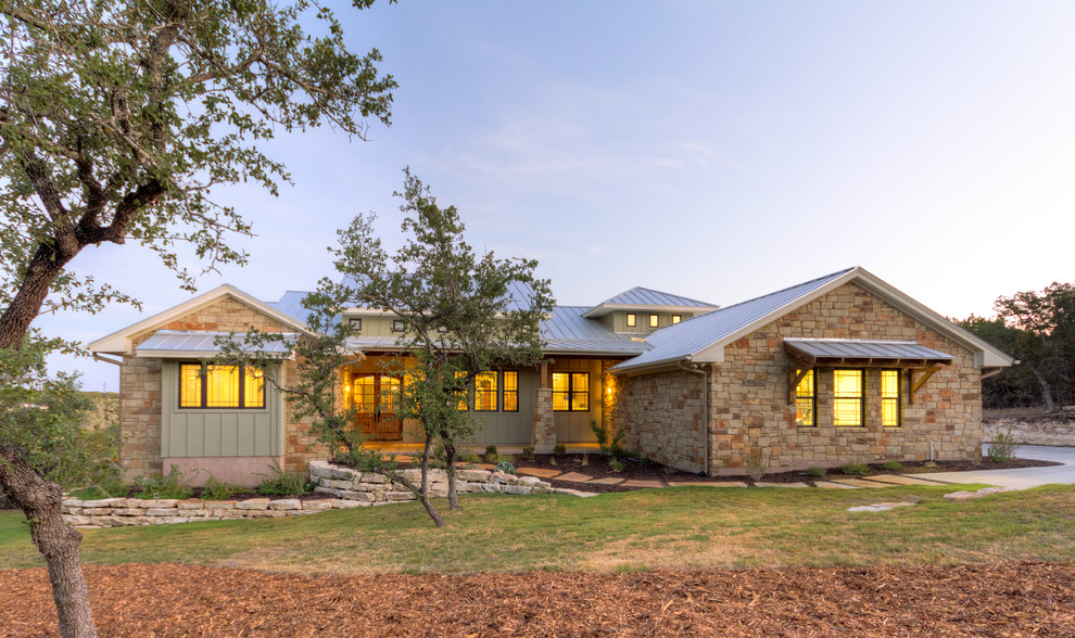 Cette image montre une grande façade de maison beige craftsman en pierre de plain-pied avec un toit en métal.