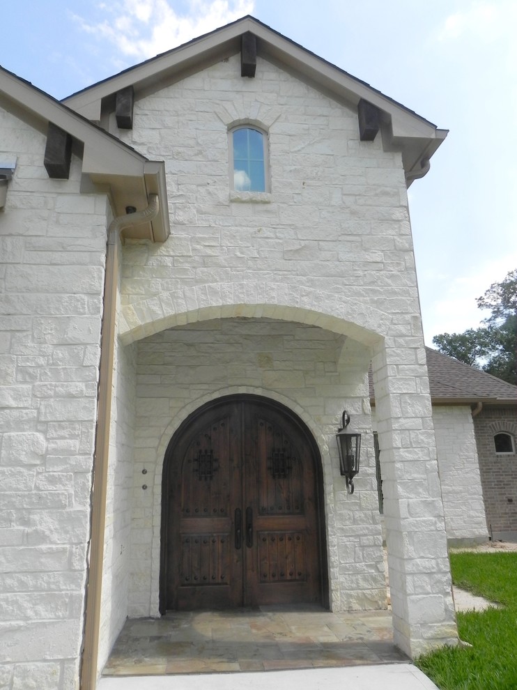 Esempio della facciata di una casa ampia bianca a un piano con rivestimento in pietra