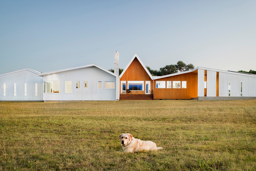 Immagine della villa bianca contemporanea a un piano di medie dimensioni con rivestimento in metallo, tetto a capanna e copertura in metallo o lamiera