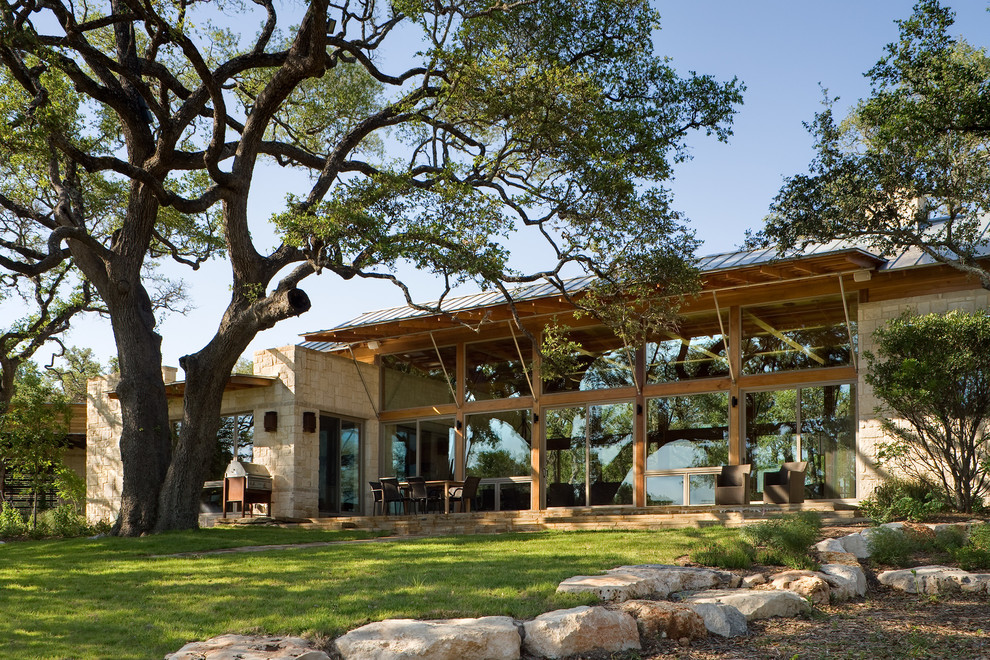 Design ideas for a rustic house exterior in Austin with stone cladding.
