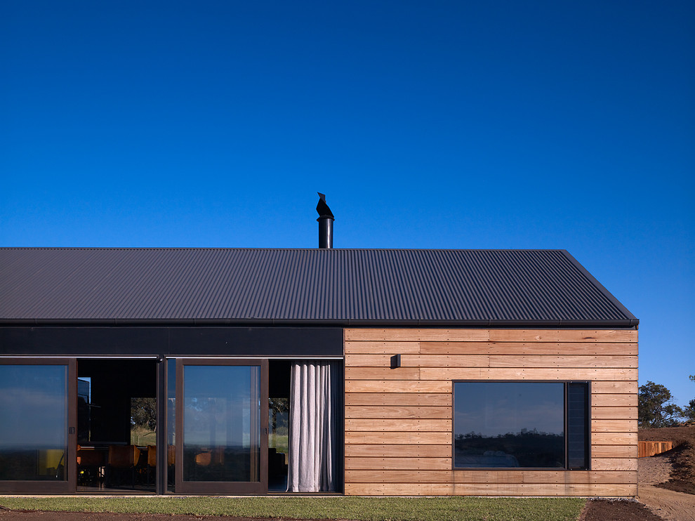 Inspiration pour une façade de maison noire rustique en bois de taille moyenne et de plain-pied avec un toit en appentis.