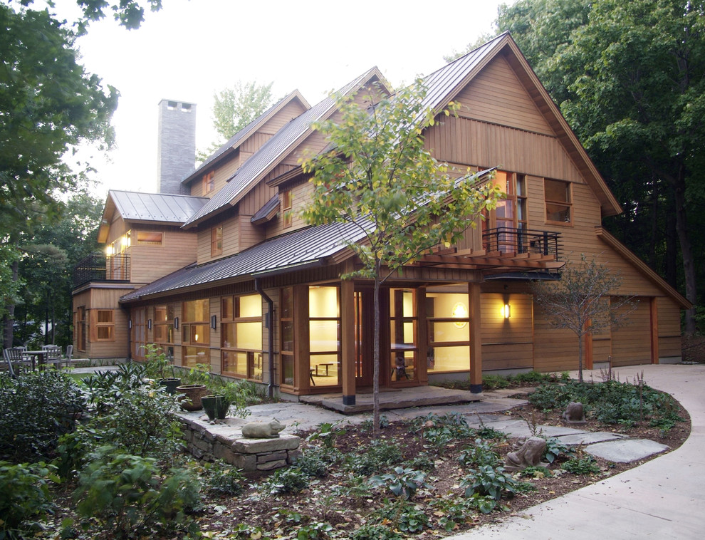 Imagen de fachada de casa beige rústica grande de dos plantas con revestimiento de madera y tejado de metal