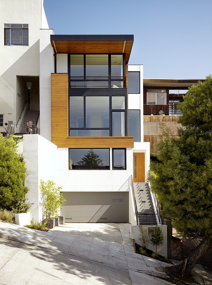 Immagine della facciata di una casa moderna con rivestimento in legno e terreno in pendenza