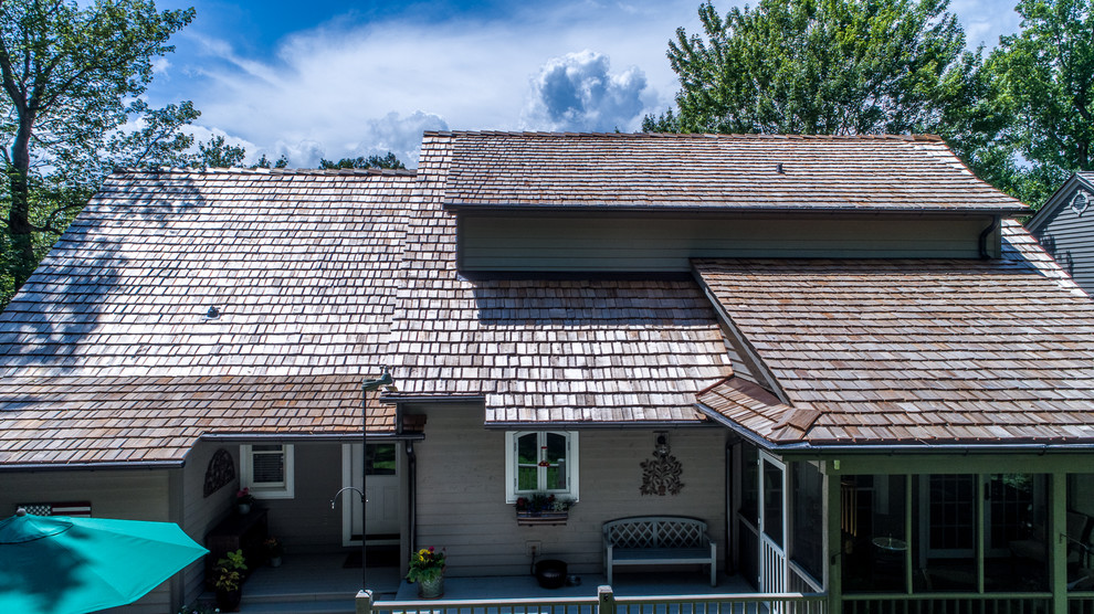 Immagine della villa grande grigia country a due piani con tetto a capanna e copertura a scandole