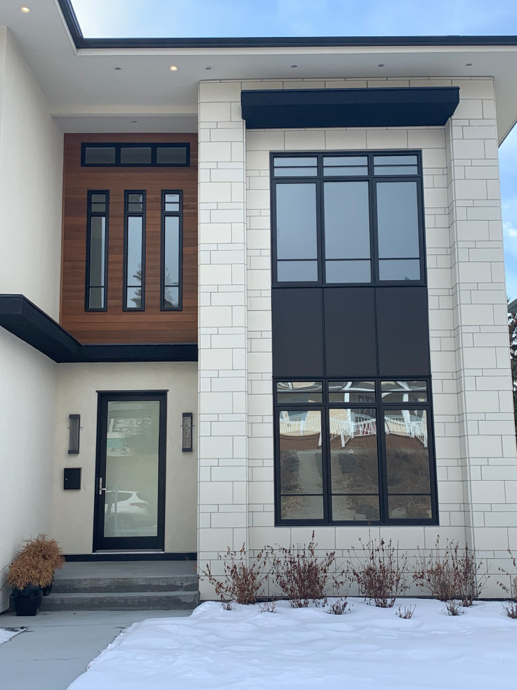 Kleines, Zweistöckiges Modernes Einfamilienhaus mit Steinfassade, weißer Fassadenfarbe und Flachdach in Calgary