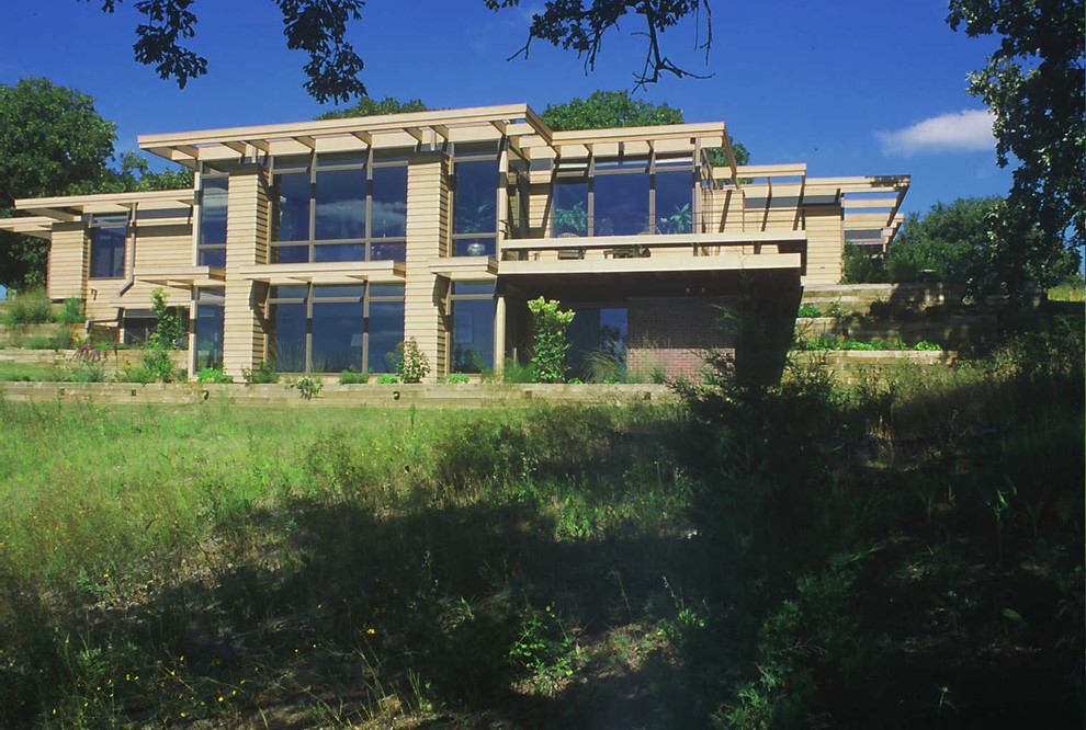 На фото: огромный, деревянный, коричневый дом в классическом стиле с разными уровнями и плоской крышей с