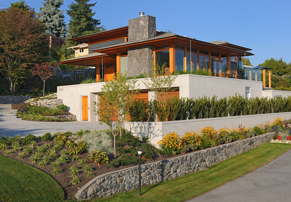 Diseño de fachada de casa gris actual grande de tres plantas con revestimientos combinados y tejado a cuatro aguas